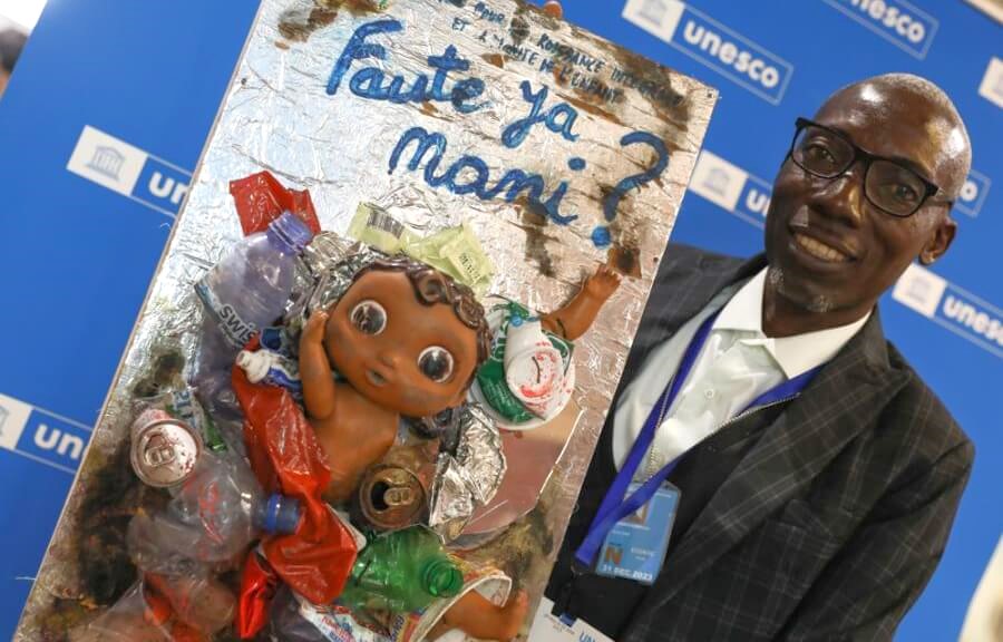 Adolphe Tungilu Luwana, Office for the Integrated Growth and Dignity of the Child (BCIDE), holds a piece of art from plastic waste, made by children in the Democratic Republic of the Congo, that asks 'whose fault is this?'