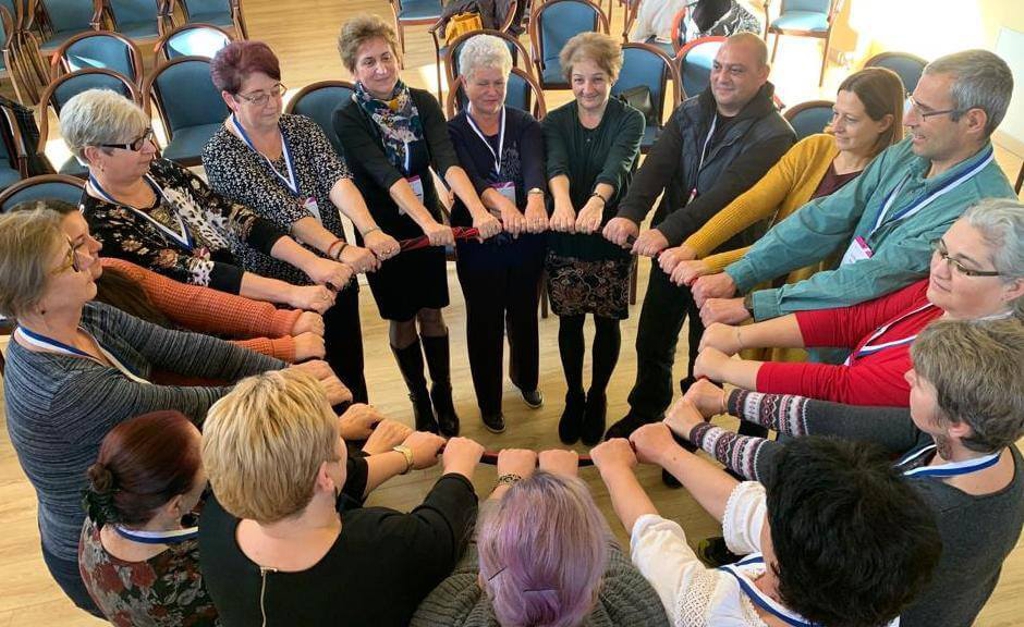 Domestic Violence Prevention Workshop - people in a circle with arms stretched toward center holding a large hoop