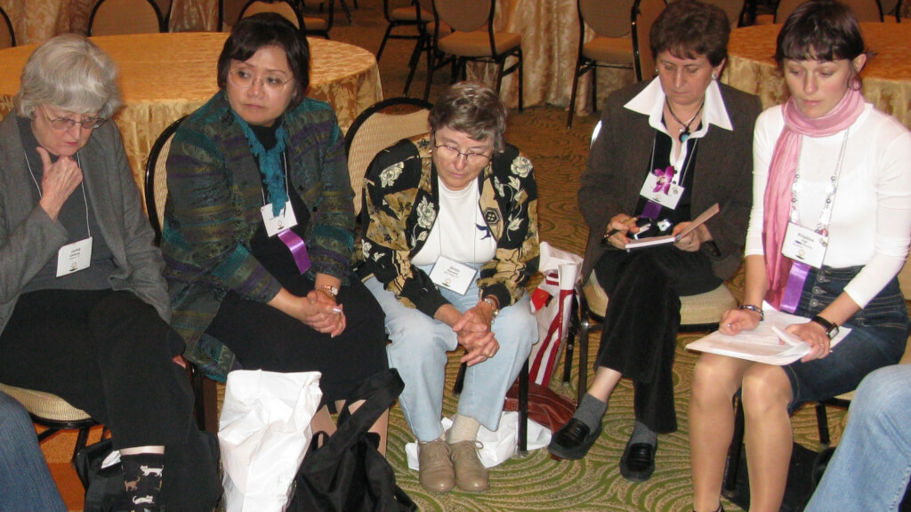 A Global Sisters Group with women from Japan, Romania and the US - 5 women sitting in a semi-circle looking thoughtful