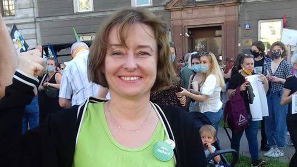 Justyna at the demonstrations - a woman with light brown hair wearing a lime green shirt in front of a crowd of people outdoors
