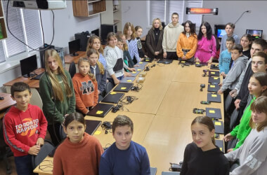 Laptops to Ukraine in 2023 - classroom full of children standing around a long table with laptop computers on it