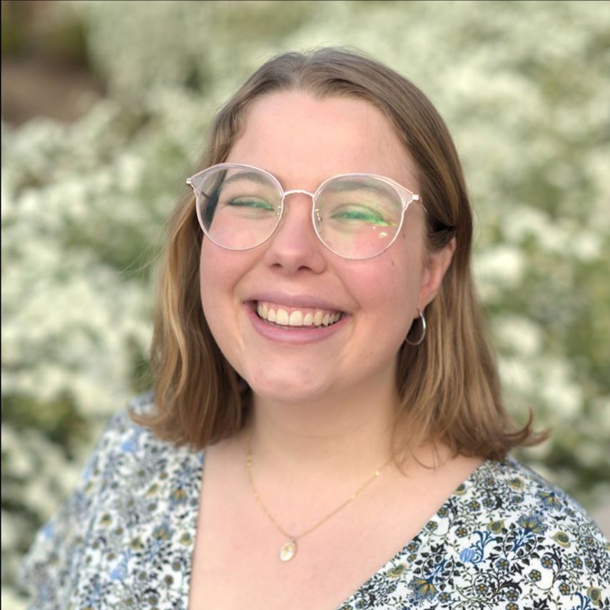 Zoë Johnston - young woman with shoulder-length light brown hair, wearing glasses and a flower print v-neck shirt