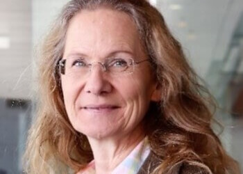 Tina Huesing - portrait of a woman wearing glasses, with long blonde hair and a pleasant smile